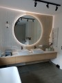 Okrągłe lustro z podświetleniem zamontowane w nowoczesnej łazience.
