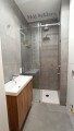 Kabina prysznicowa w małej łazience. System drzwi przesuwnych, okucia w kolorze chromu. 